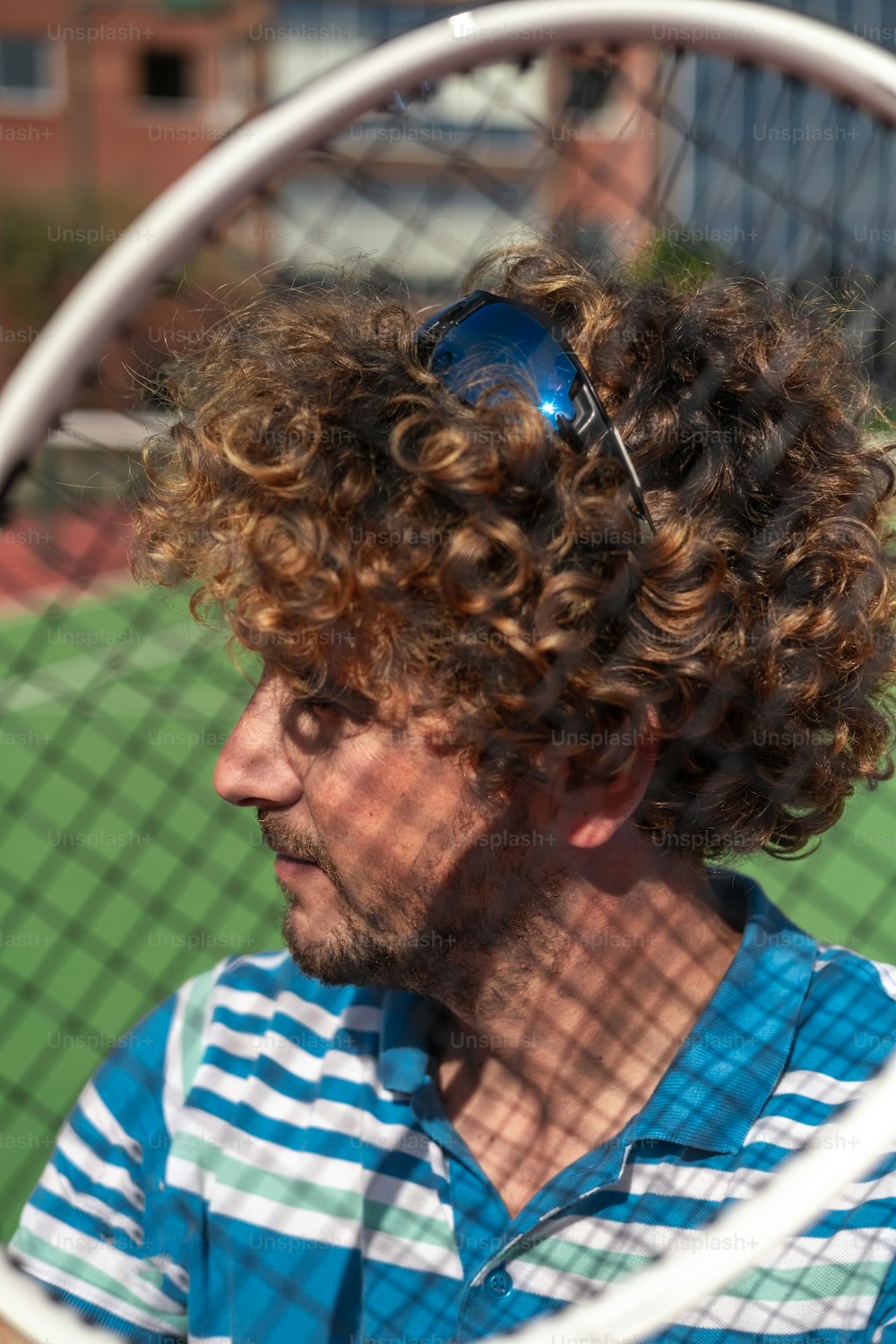 a man with curly hair holding a tennis racket