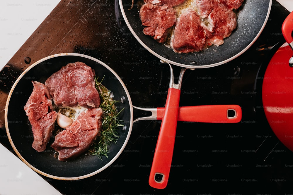 a couple of pans filled with meat on top of a stove