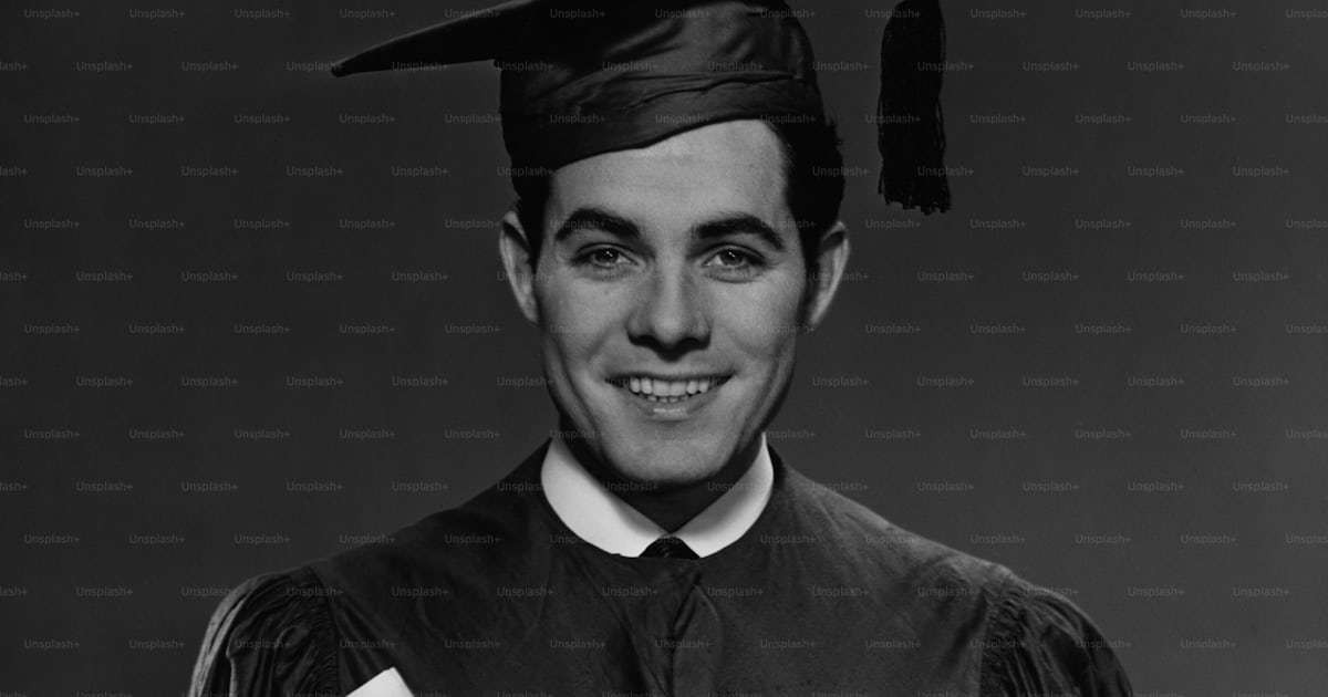 A Young Man In His Graduation Gown And Mortarboard Holding His Diploma A Young Man In His Graduation Gown And Mortarboard Holding His Diploma