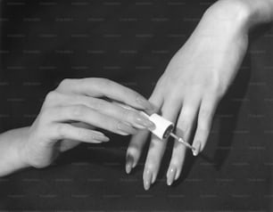VEREINIGTE STAATEN - CIRCA 1950er Jahre: Nahaufnahme von Händen, die Nagellack auftragen.