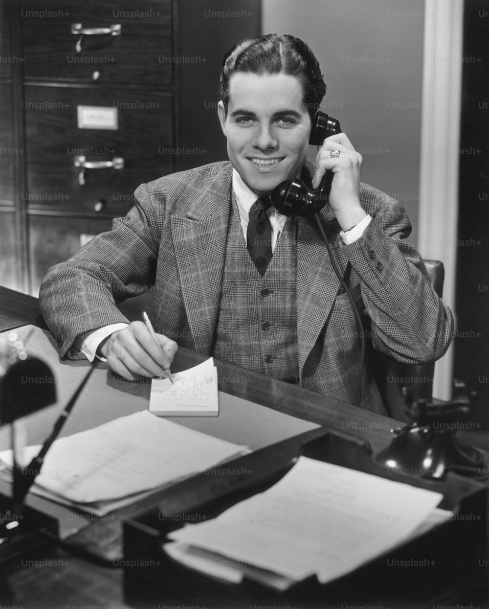 UNITED STATES - CIRCA 1950s:  Man sitting behind desk, talking on telephone.