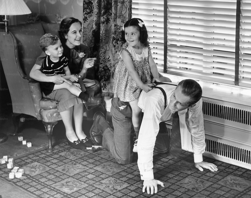 UNITED STATES - CIRCA 1950s:  Parents playing with children.