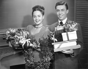 UNITED STATES - CIRCA 1950s:  Couple w/ wrapped Christmas presents.