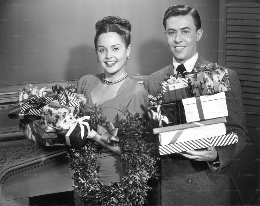 UNITED STATES - CIRCA 1950s:  Couple w/ wrapped Christmas presents.
