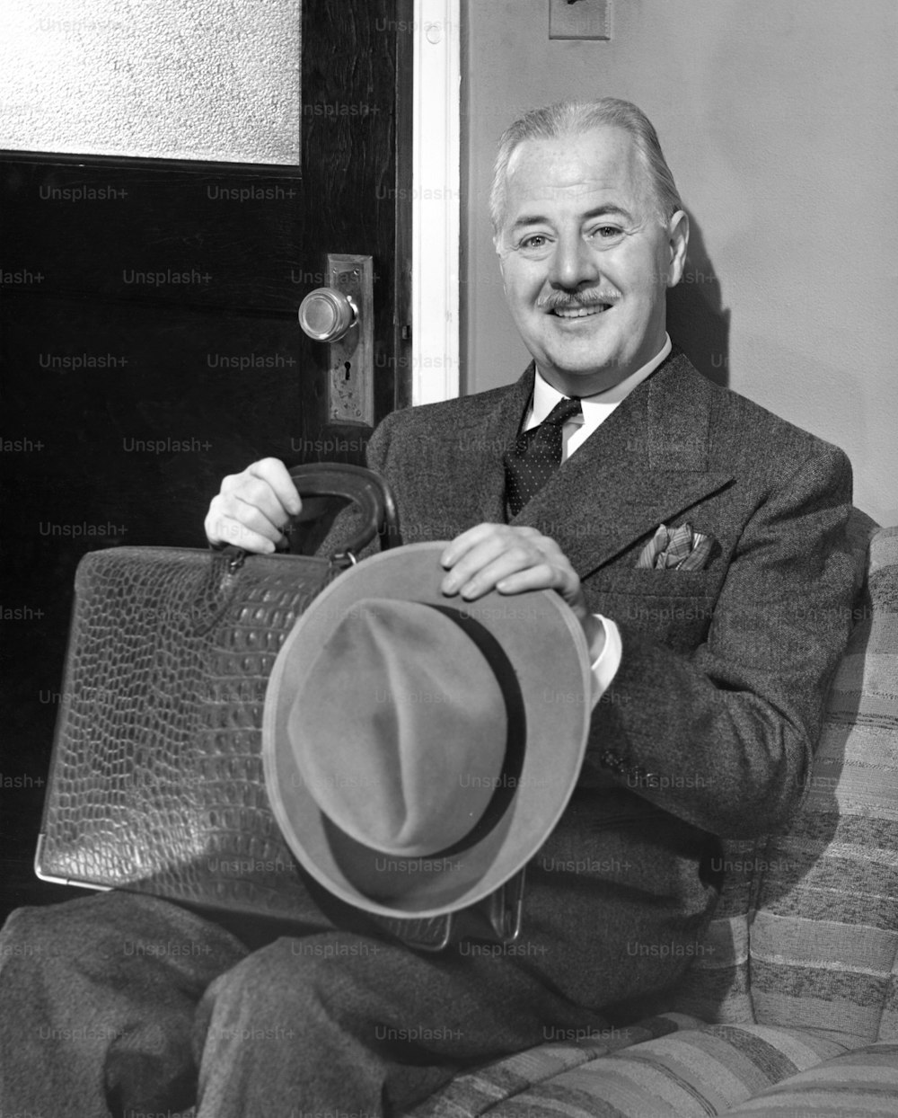STATI UNITI - CIRCA 1950: Uomo d'affari che tiene il cappello in attesa nell'ufficio esterno.