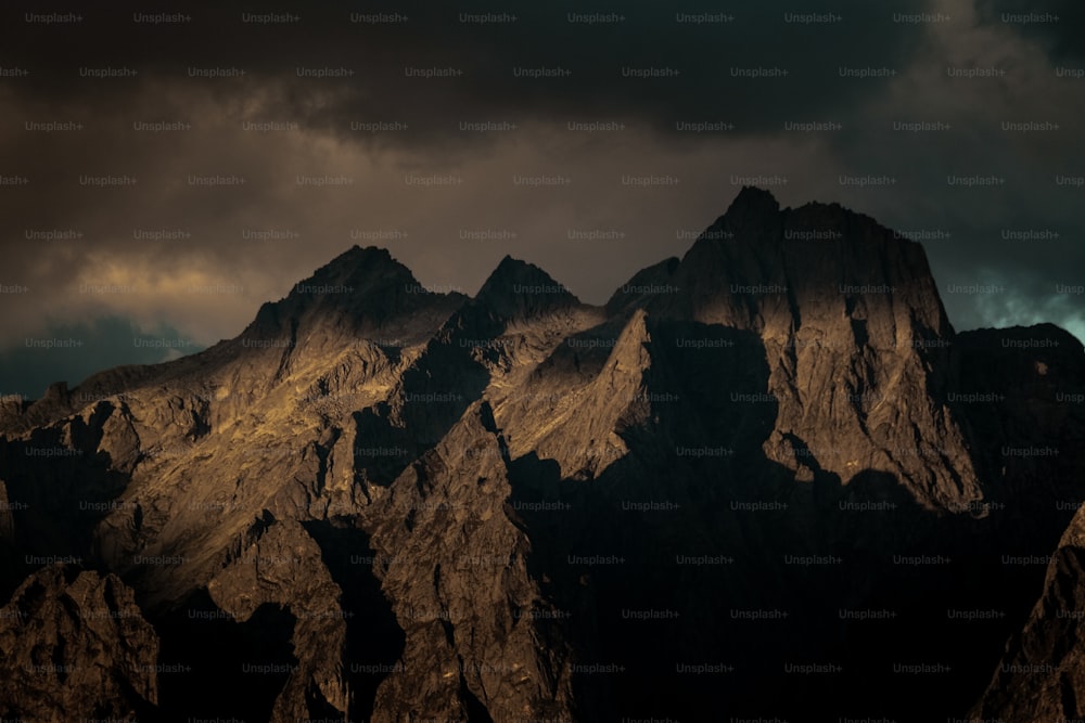Une chaîne de montagnes avec un ciel sombre en arrière-plan
