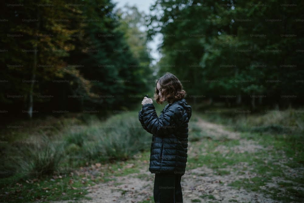 a person standing on a dirt road in the woods