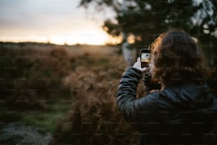 a woman taking a picture of a field with her cell phone