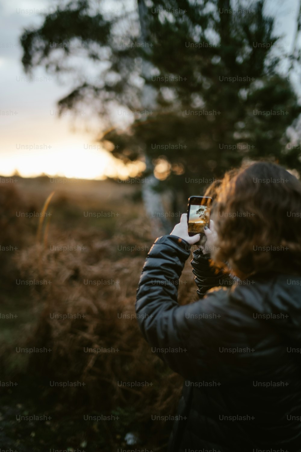 Una mujer tomando una foto de un campo con su teléfono celular