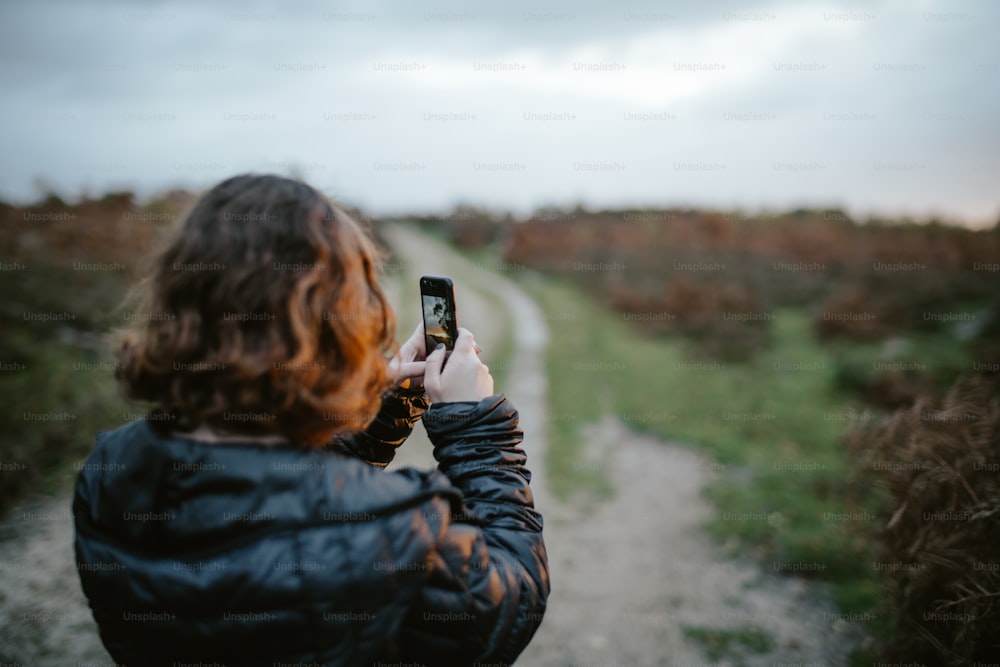 uma mulher tirando uma foto de uma estrada de terra
