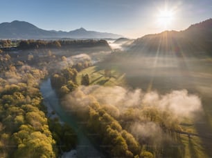 the sun shines brightly over a valley with trees in the foreground