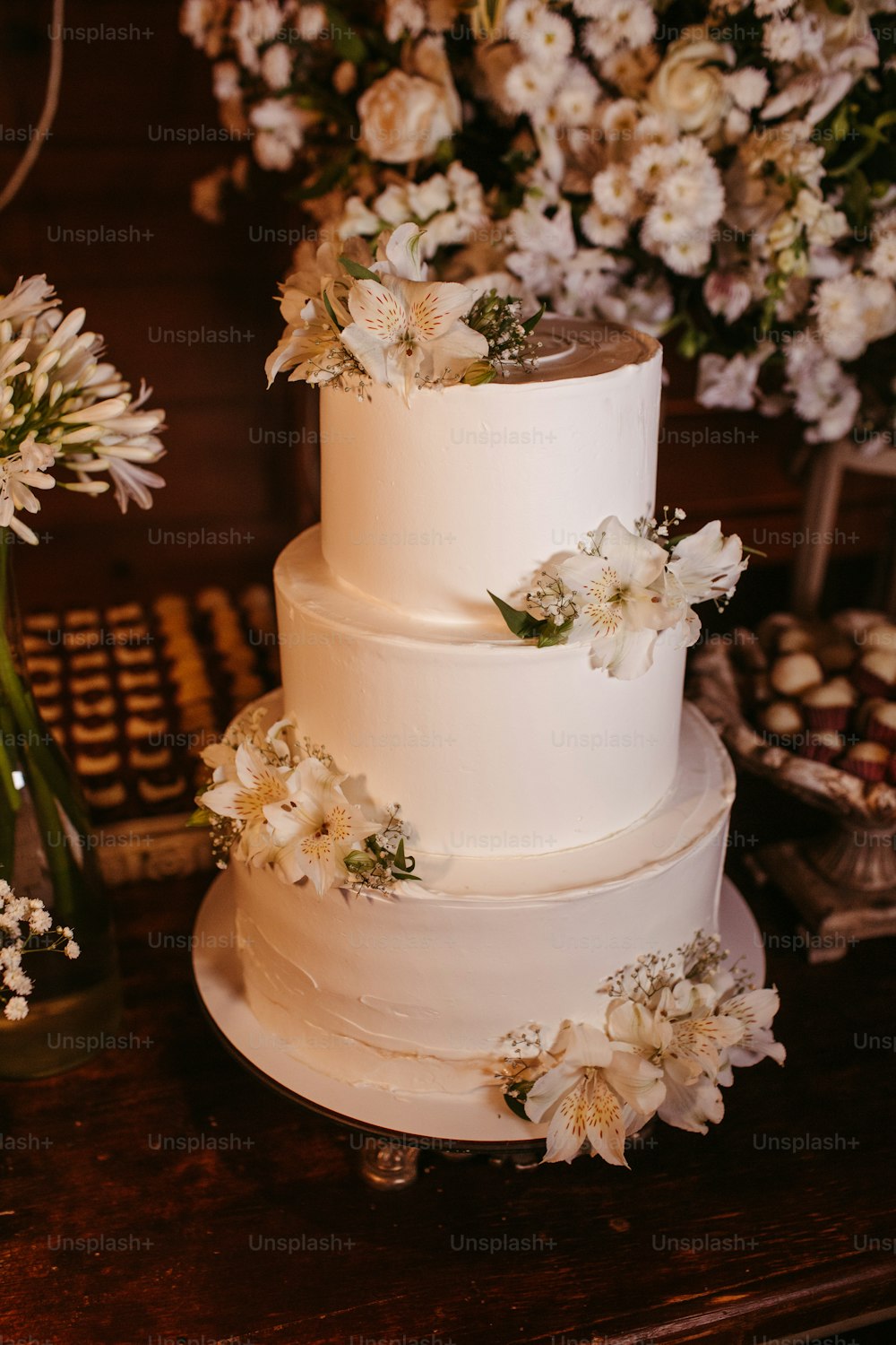 a three tiered white wedding cake with flowers on top