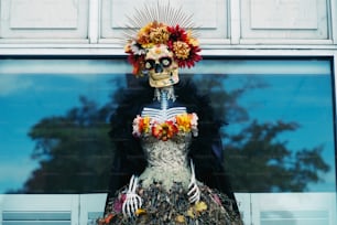 eine Statue eines Skeletts, das ein Kleid mit Blumen trägt