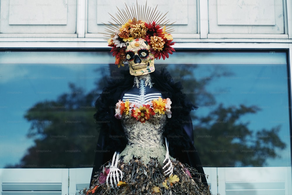 uma estátua de um esqueleto usando um vestido com flores sobre ele