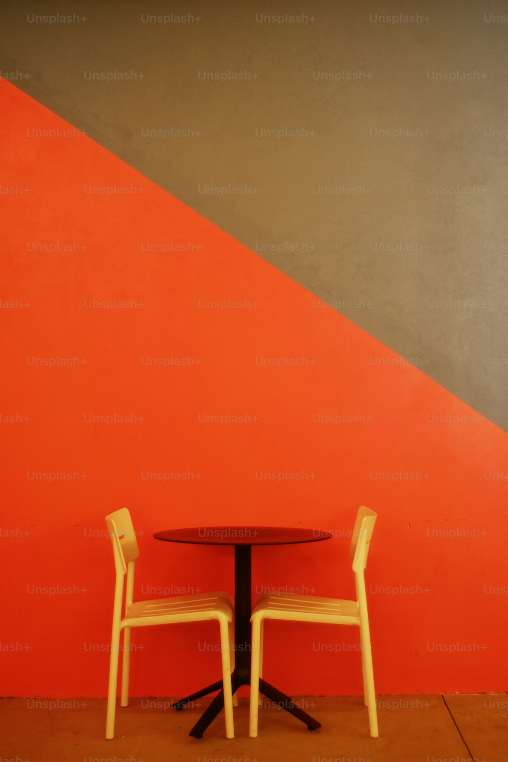 빨간 벽 앞에 의자 두 개와 탁자