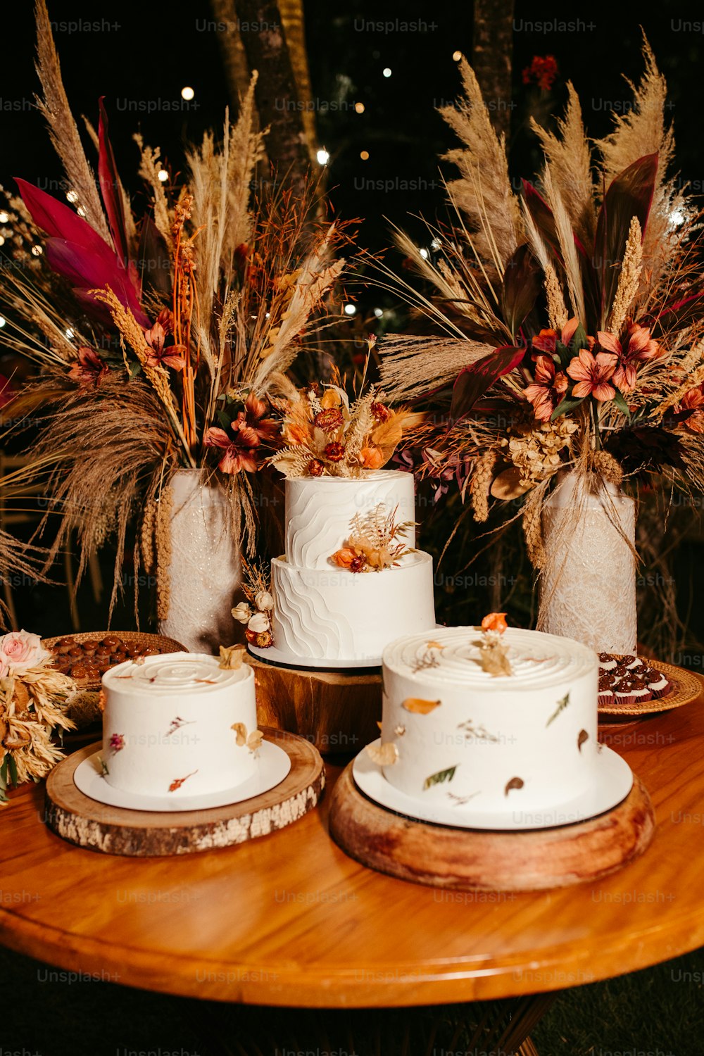 una mesa cubierta con tres pasteles blancos cubiertos de glaseado