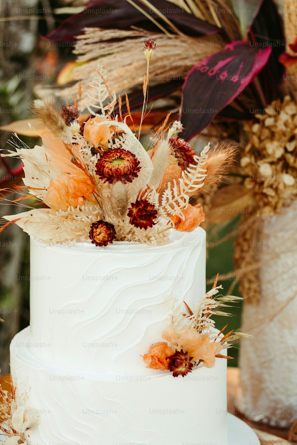 a white wedding cake with dried flowers on top