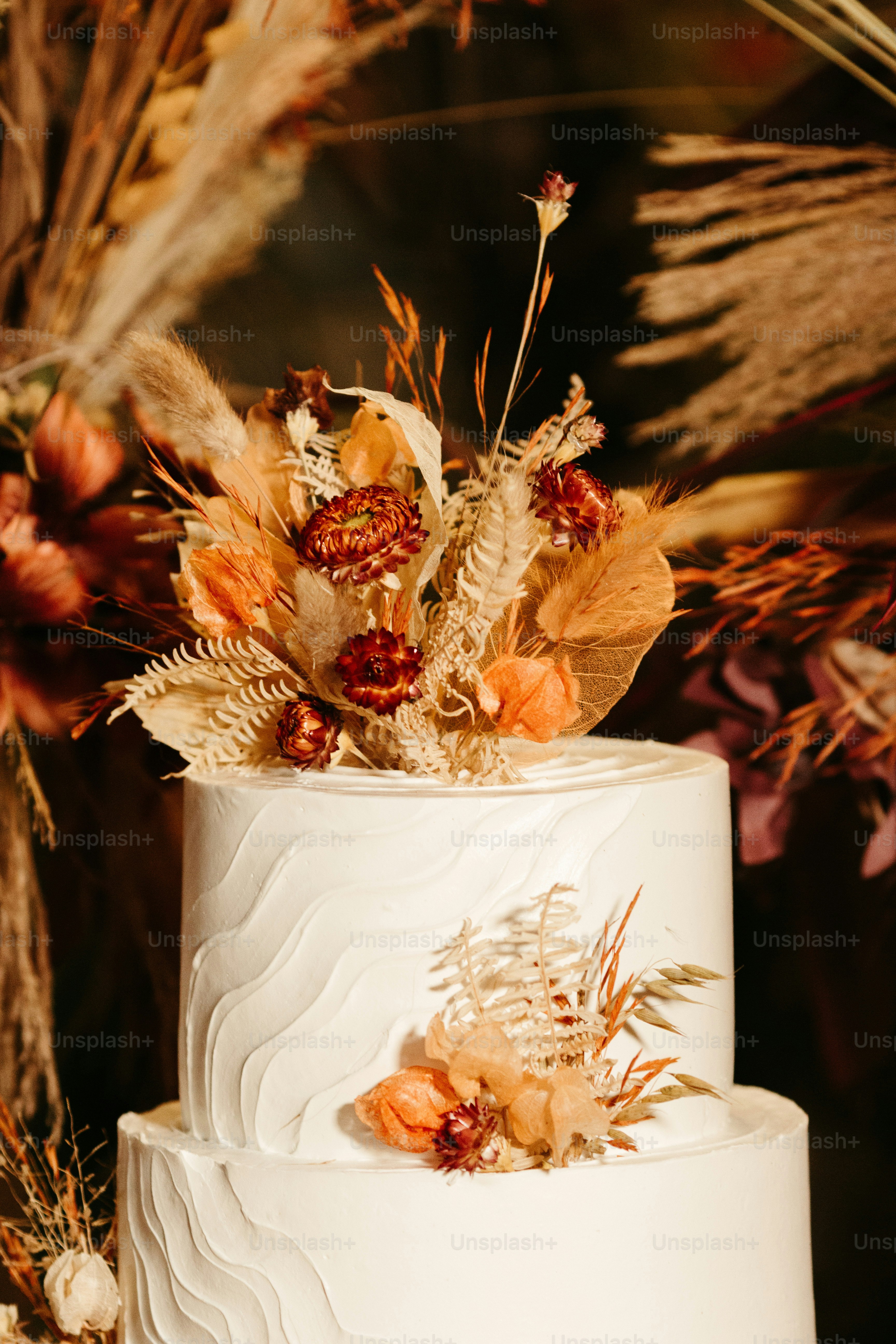 A white wedding cake with dried flowers on top photo – Wedding cake ...