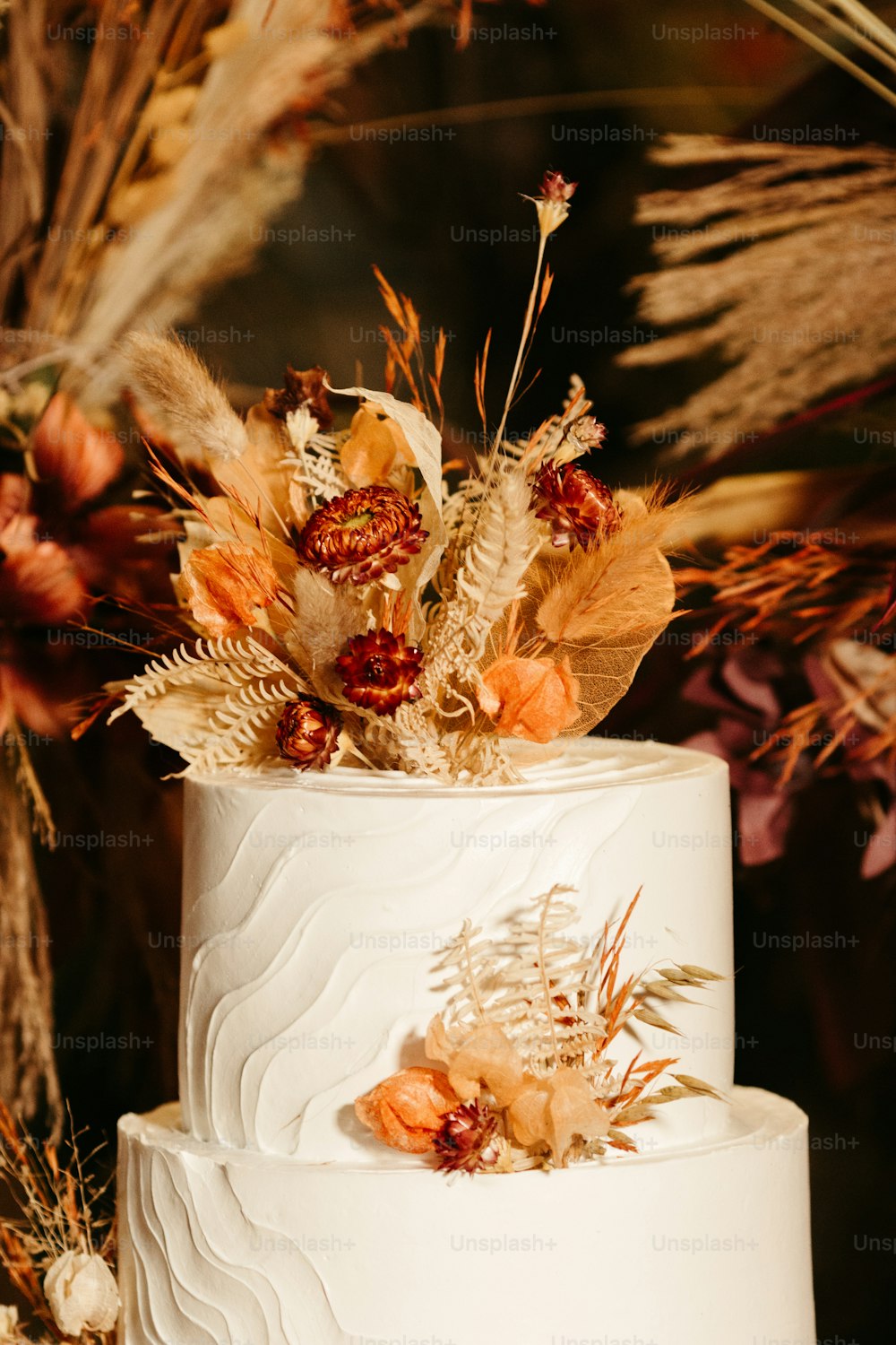 Un pastel de bodas blanco con flores secas en la parte superior
