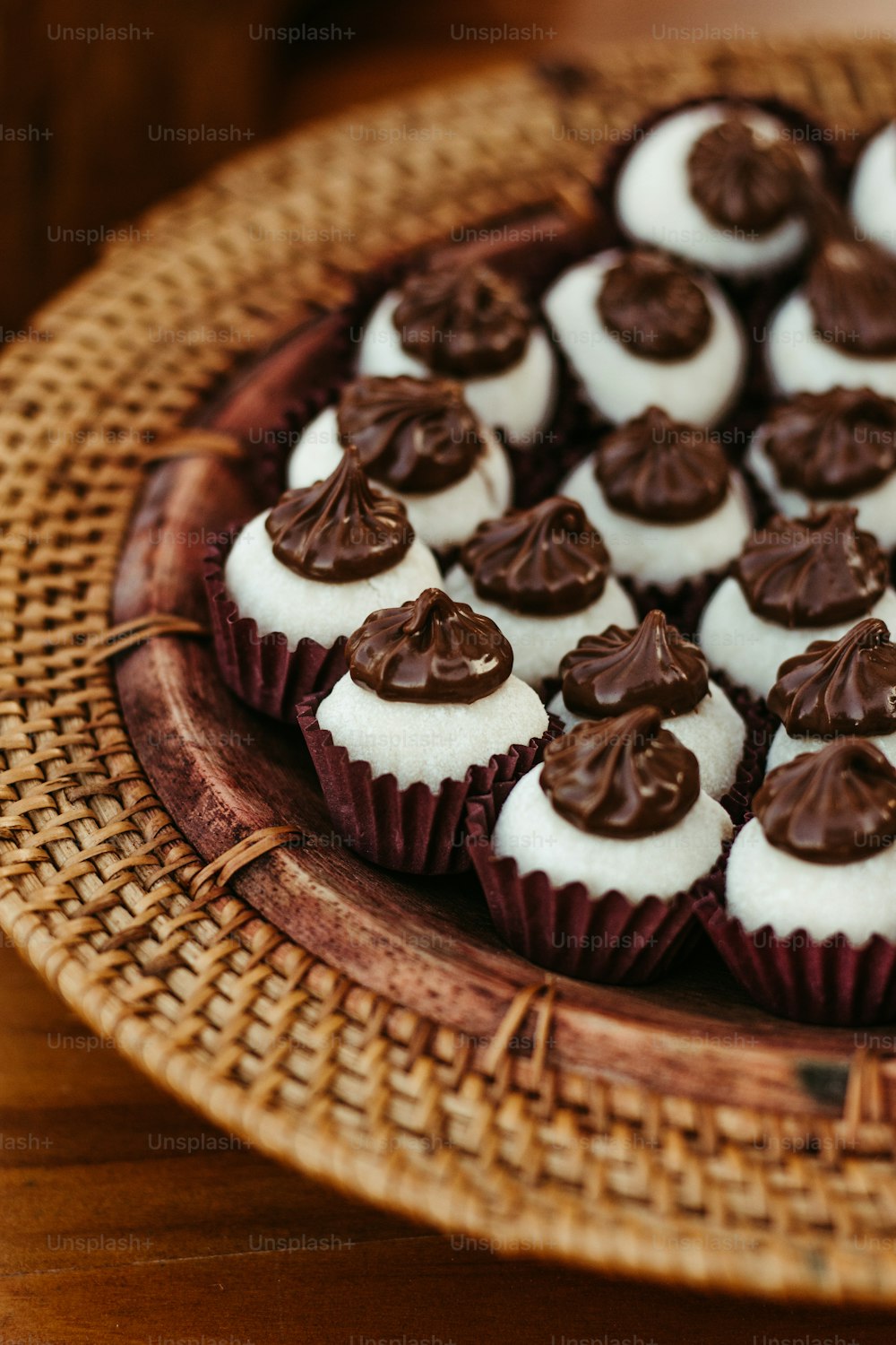 a plate of cupcakes with white frosting and chocolate decorations