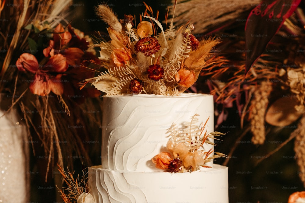 Un pastel de bodas blanco de tres niveles con flores secas