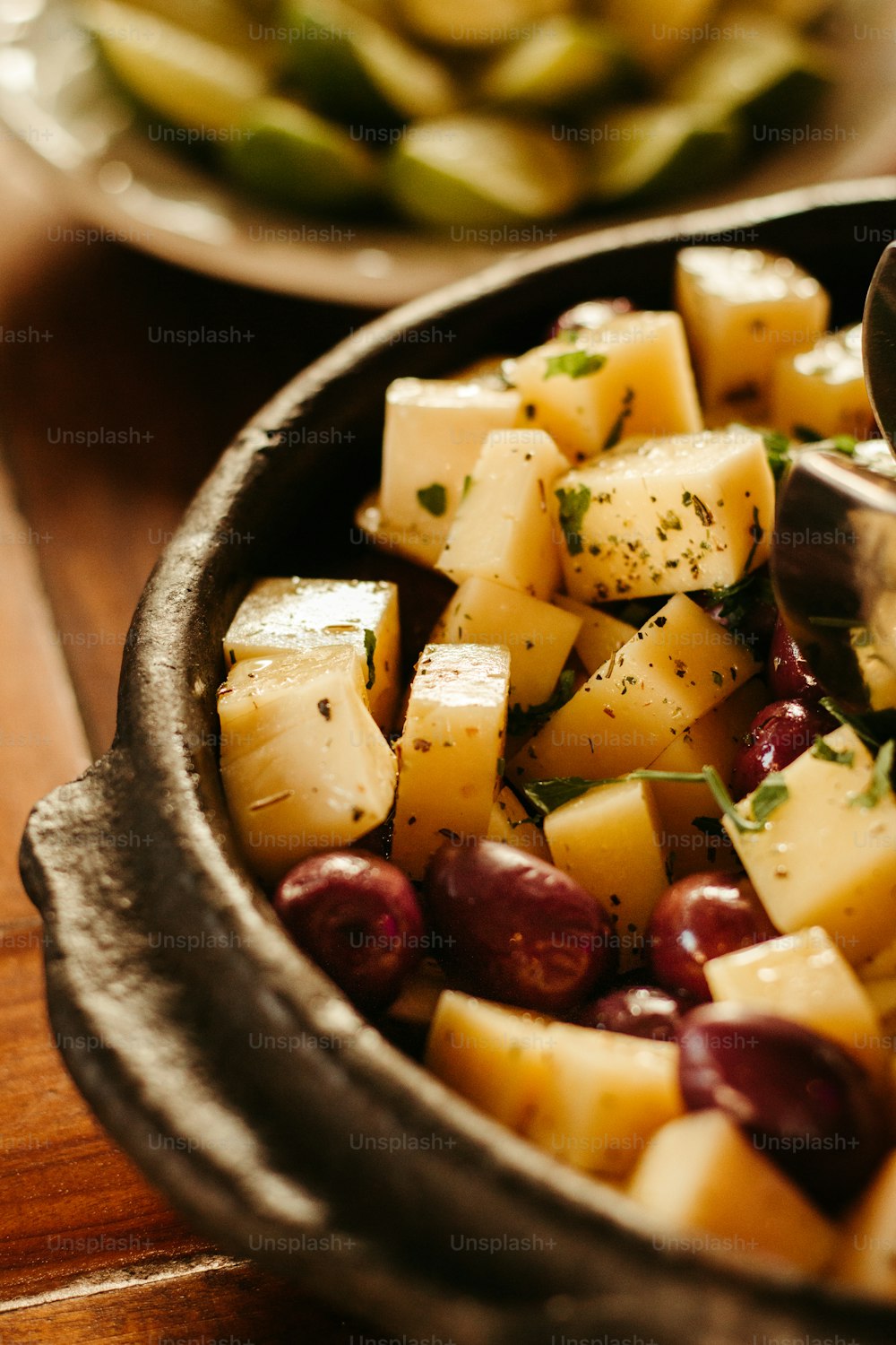 a bowl filled with potatoes and olives on top of a wooden table