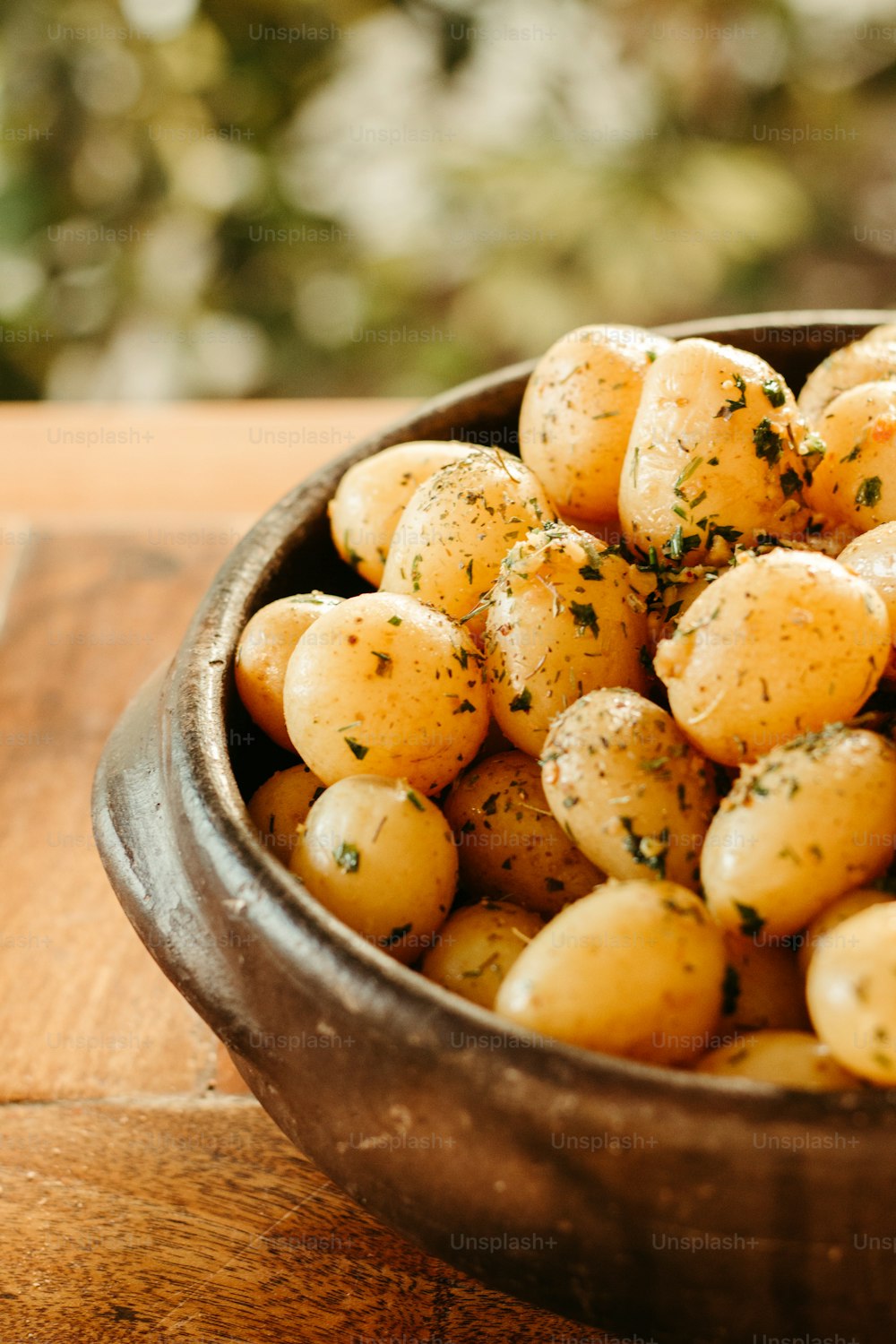 a wooden bowl filled with potatoes on top of a wooden table