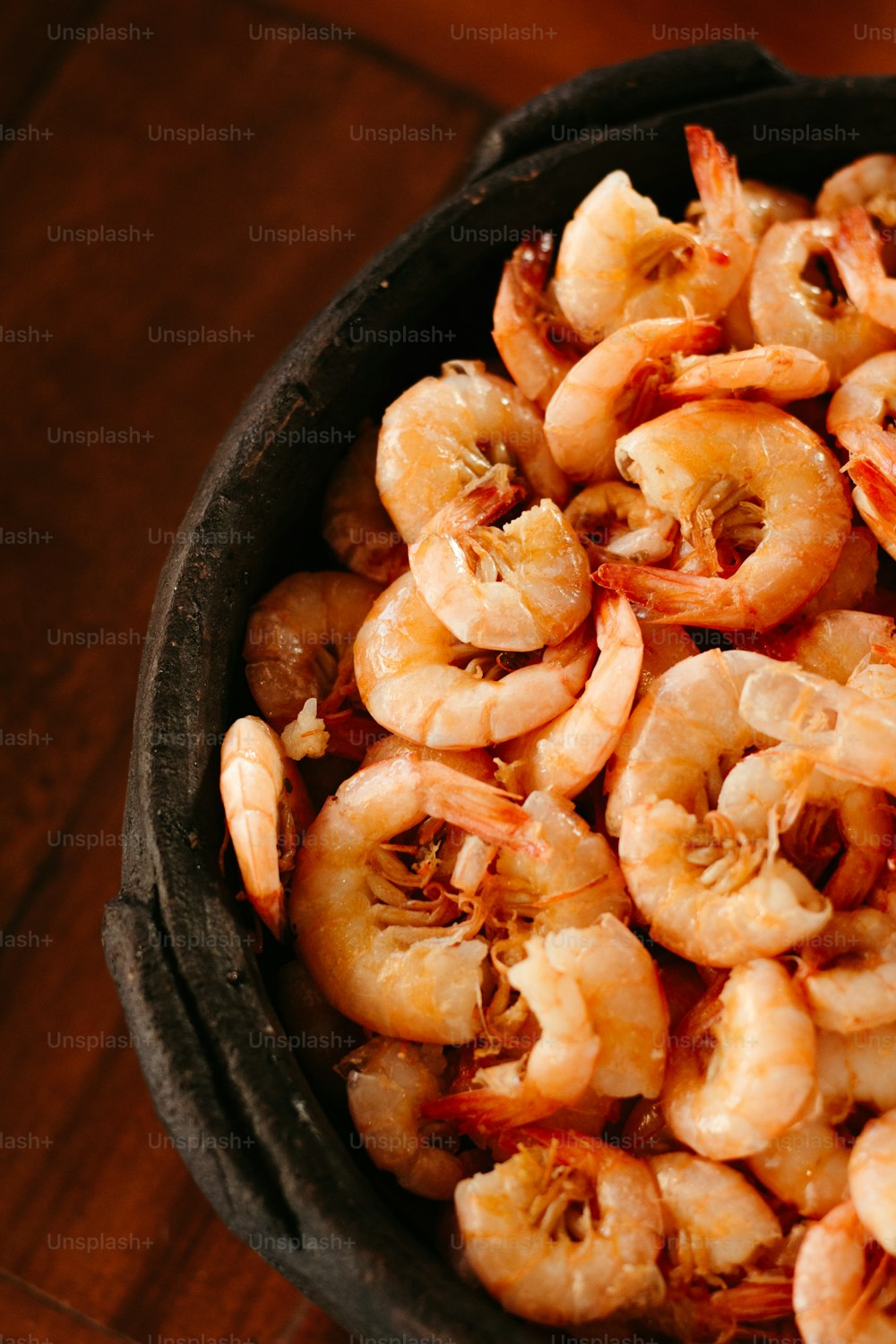 a bowl filled with cooked shrimp on top of a wooden table