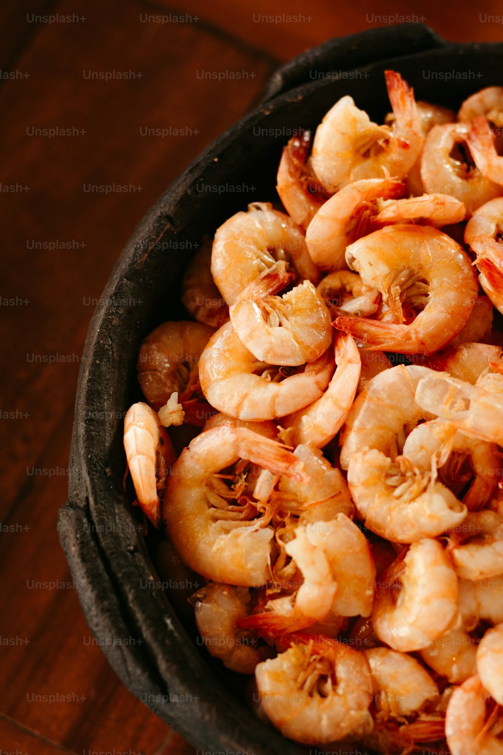 un bol rempli de crevettes cuites sur une table en bois