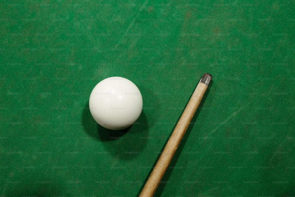 uma mesa de bilhar com um taco de bilhar e bola