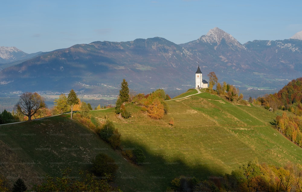 Una iglesia en una colina con montañas al fondo