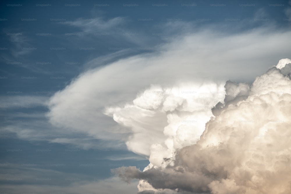 a large cloud is in the sky with a plane in the foreground