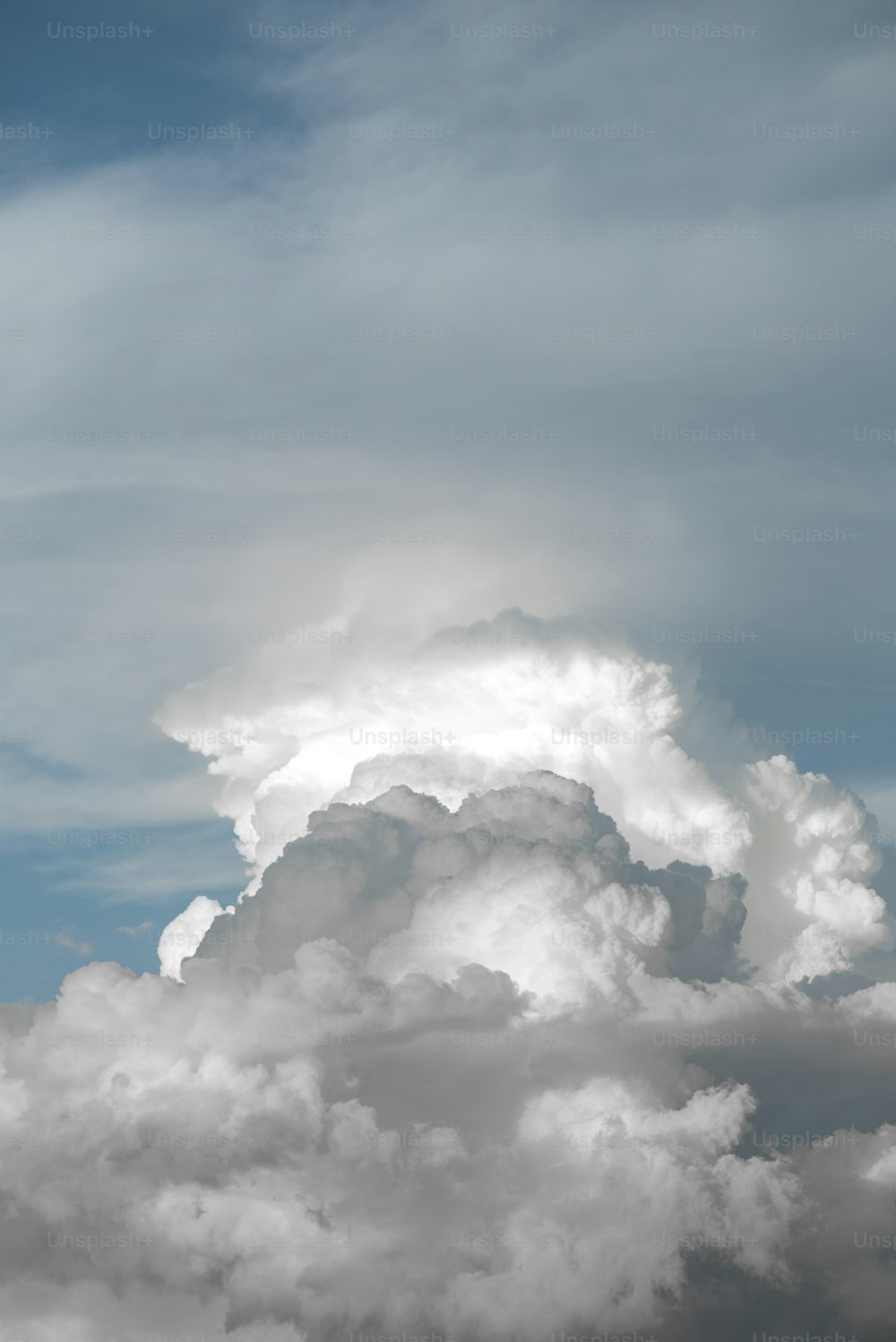 a plane flying through a cloudy blue sky