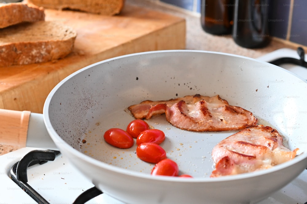 a pan filled with meat and tomatoes on top of a stove