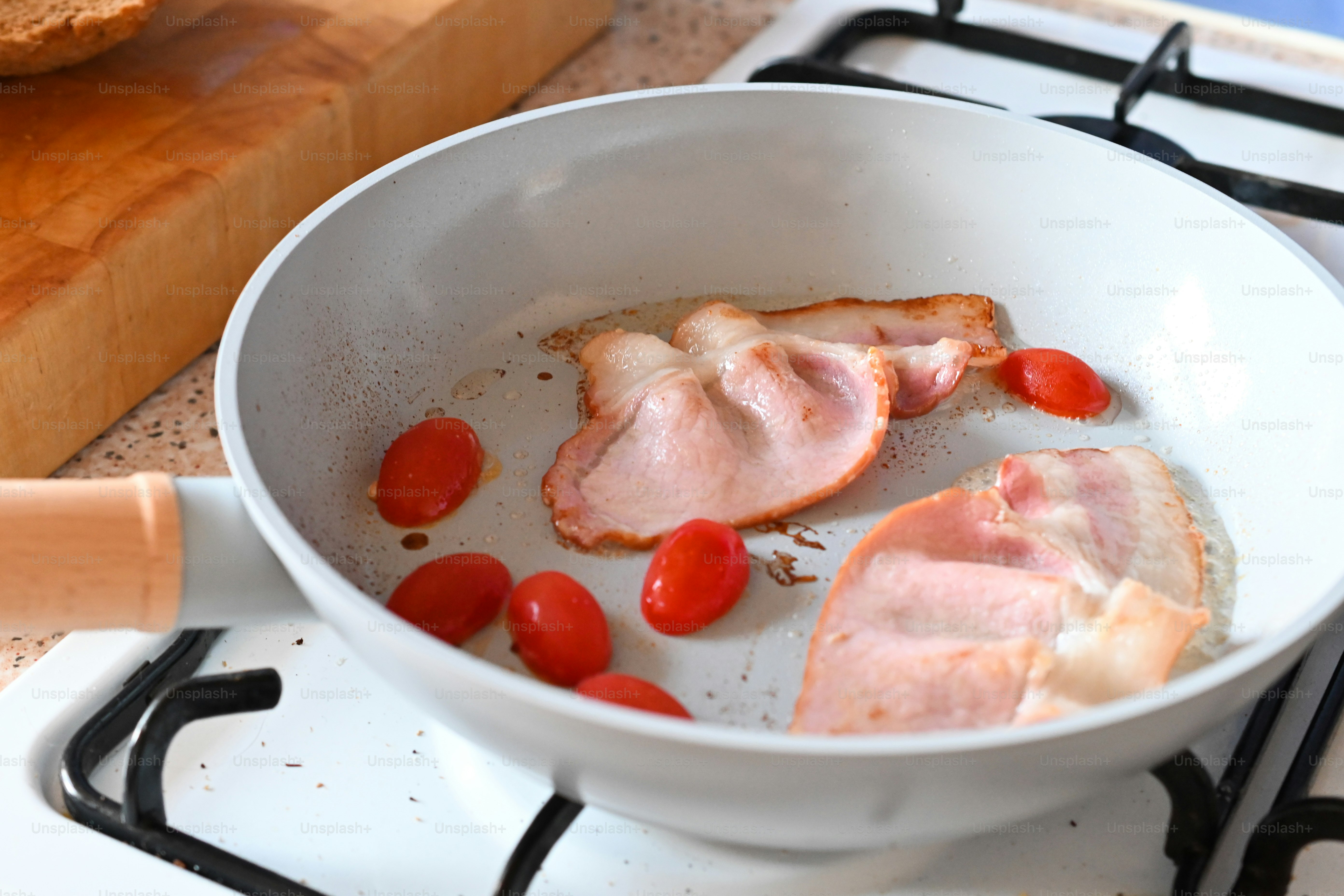 A pan filled with meat and tomatoes on top of a stove photo Bacon