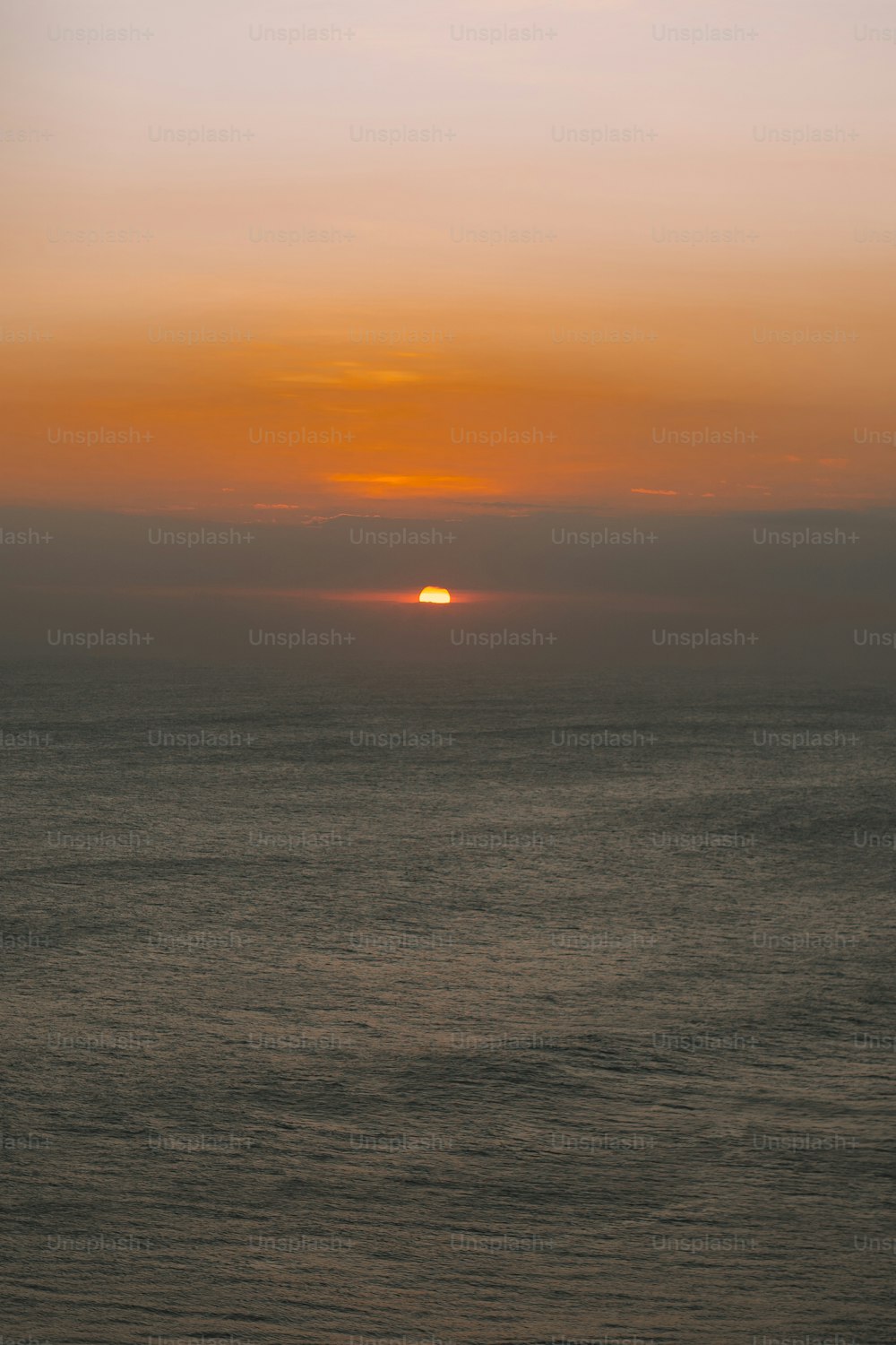 Il sole sta tramontando sull'oceano in una giornata nebbiosa