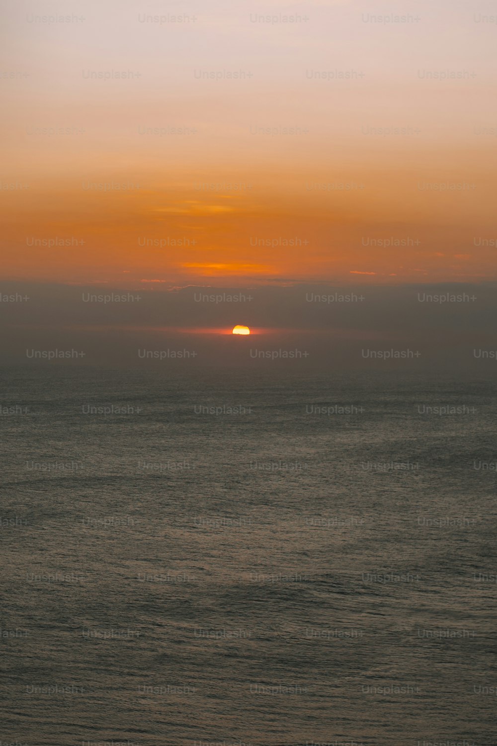 the sun is setting over the ocean on a hazy day