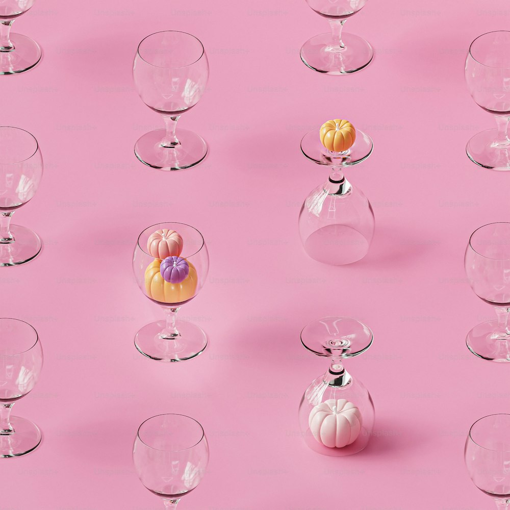 Un grupo de jarrones de vidrio sentados sobre una superficie rosa