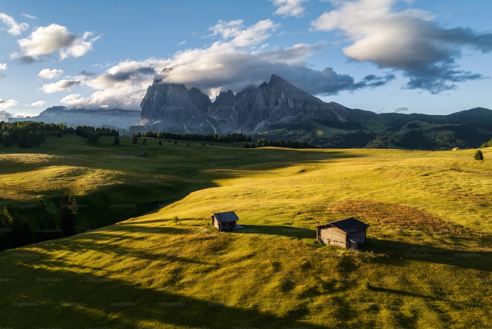 two small houses in a grassy field with mountains in the background