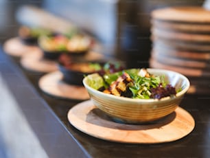 uma tigela de salada sentada em cima de um prato de madeira