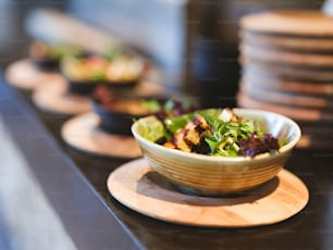 a bowl of salad sitting on top of a wooden plate