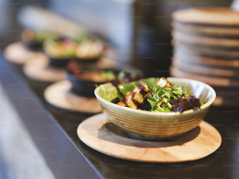 a bowl of salad sitting on top of a wooden plate
