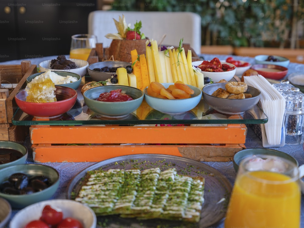 ein Tisch gefüllt mit Tellern mit Essen und Schalen mit Obst