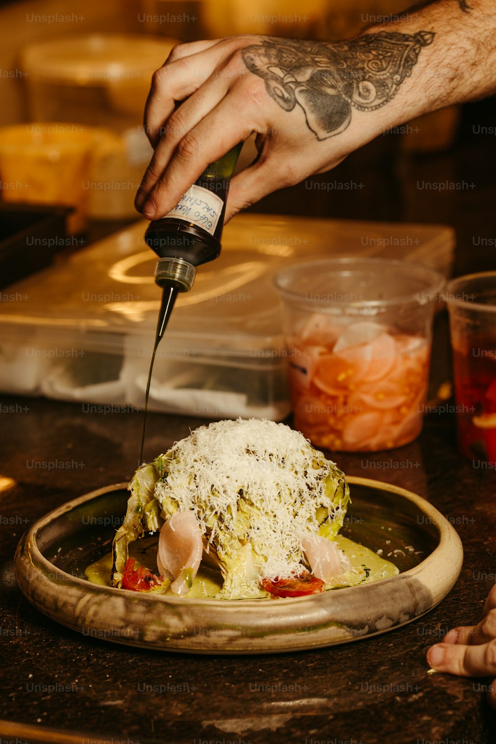 a person pouring sauce on a dish of food