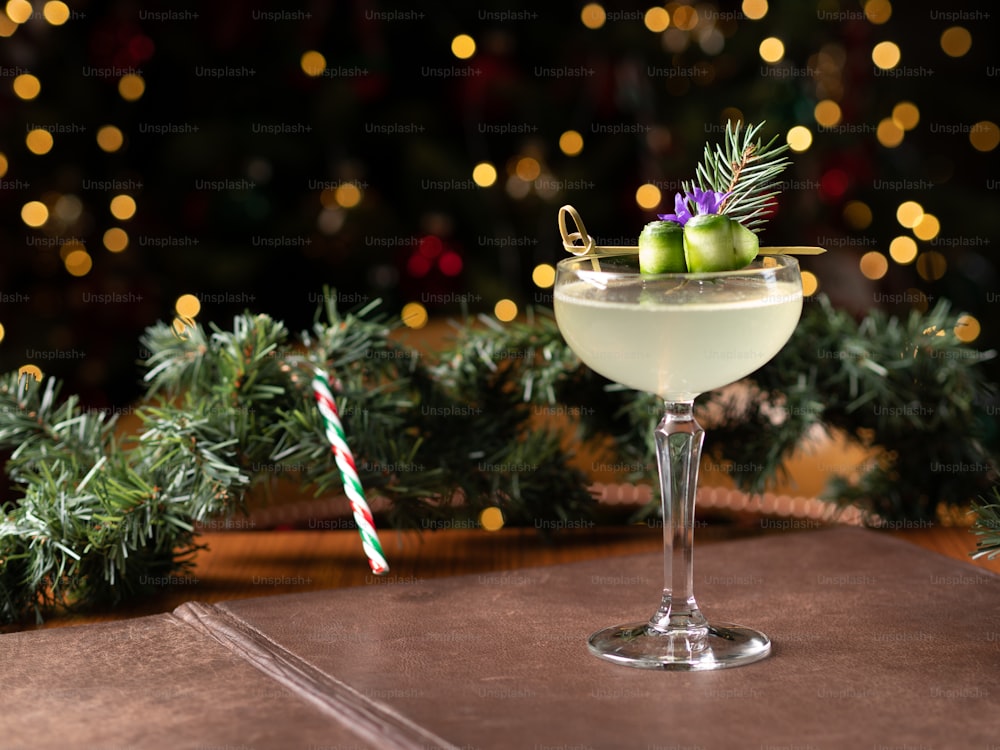 a drink in a glass with a christmas tree in the background