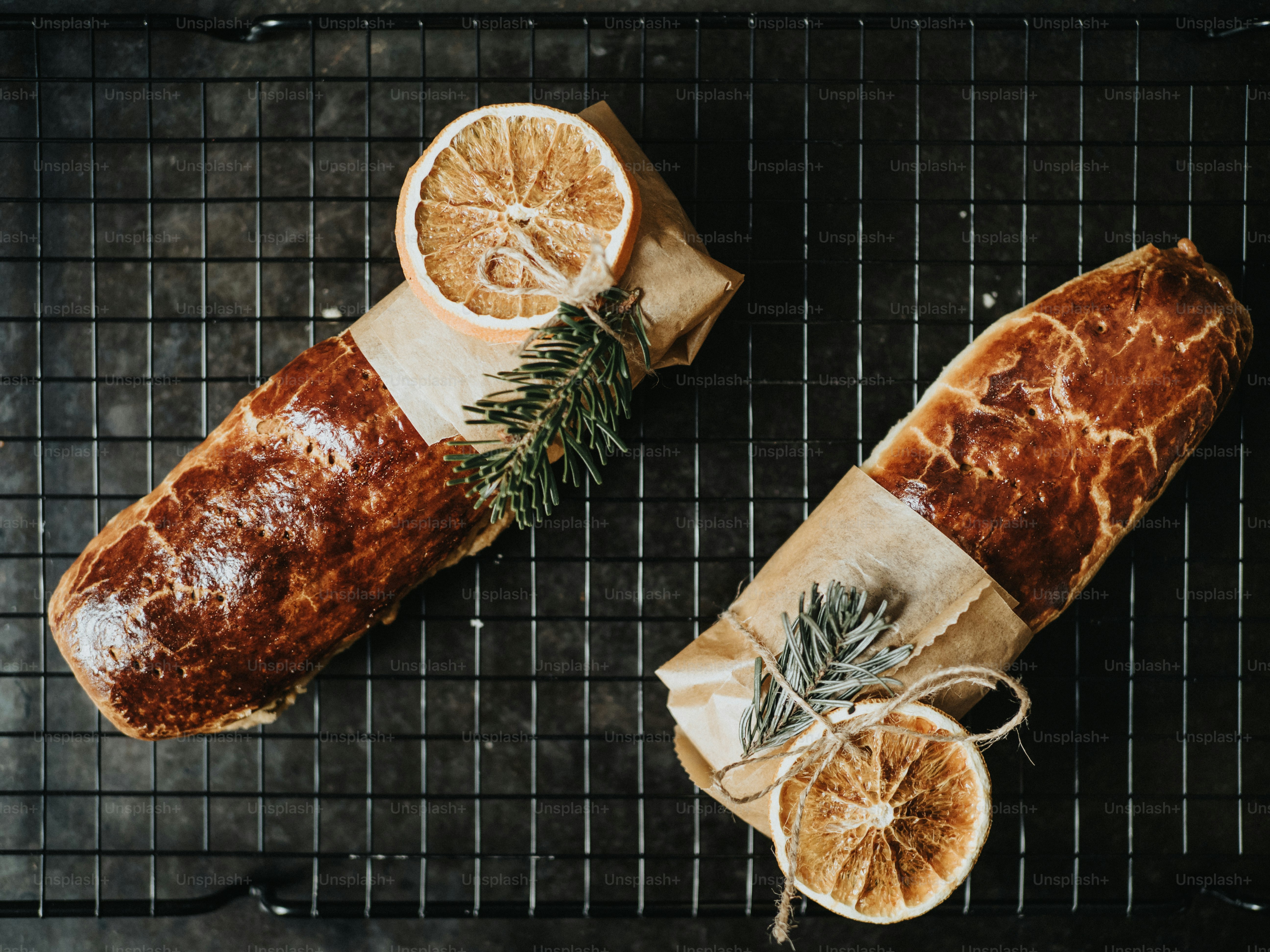 a loaf of bread with a slice of orange and a sprig of rosemary
