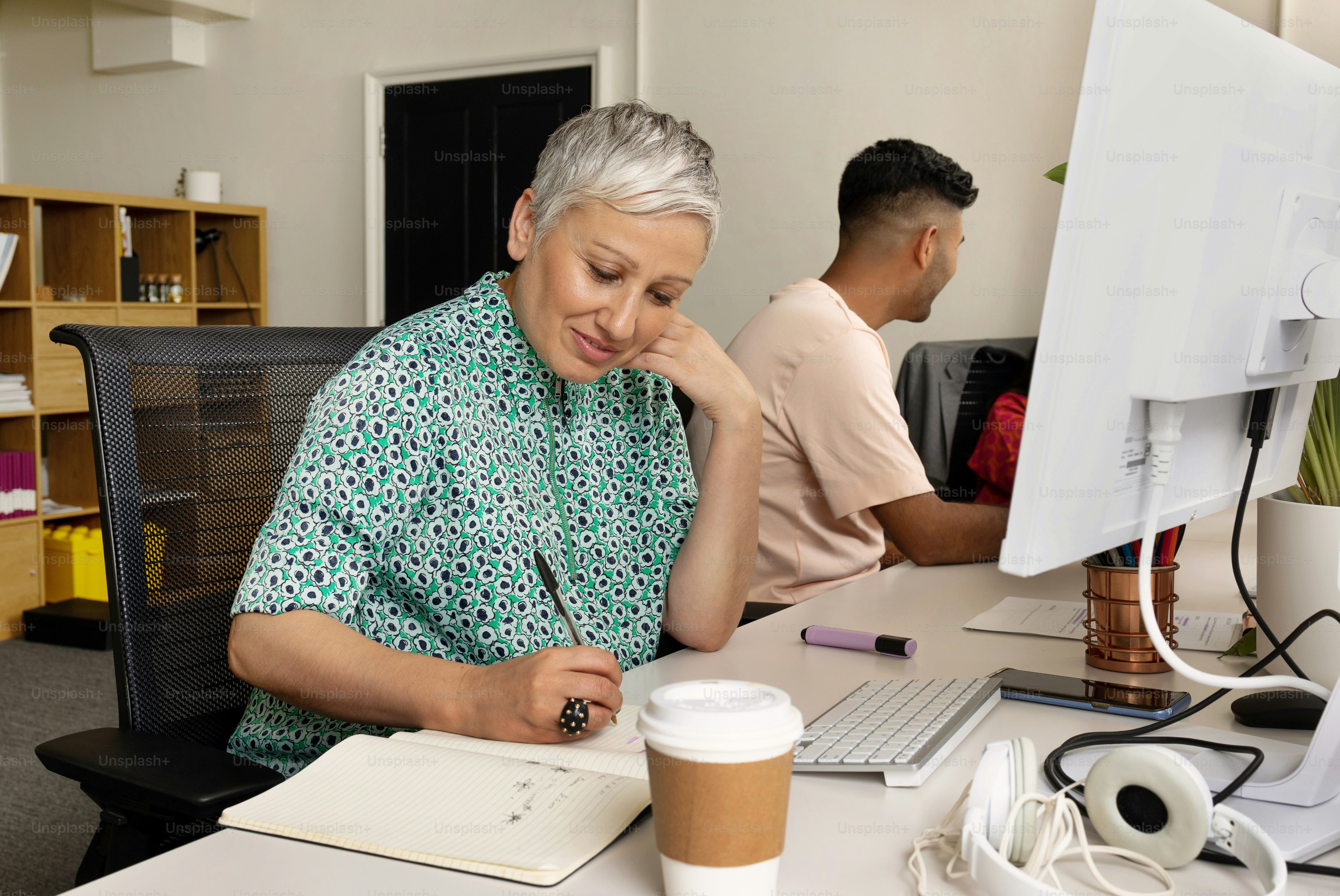 a woman sitting at a desk with a cup of coffee