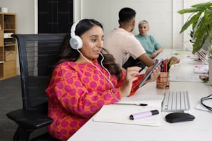 Una mujer sentada en un escritorio con auriculares puestos