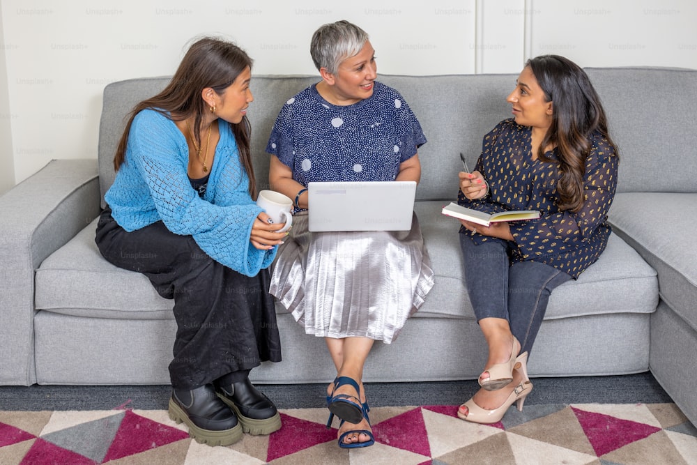 three women sitting on a couch talking to each other