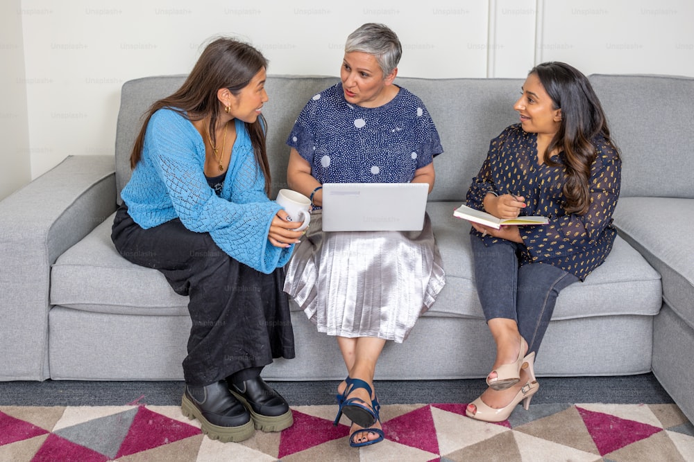 three women sitting on a couch talking to each other